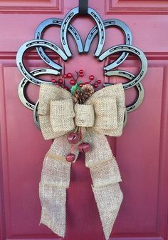 a door with a wreath and bells hanging on it's side, in front of a pink door