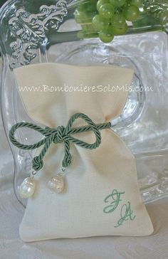 a bag with some pearls on it sitting next to a vase filled with green grapes