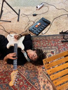 a man laying on the floor with an electric guitar