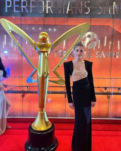 a woman standing next to a golden statue