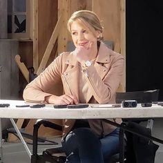 a woman sitting at a table with her hands on her chin and looking to the side