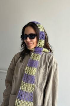 a woman wearing sunglasses and a knitted scarf in shades of purple, yellow and green