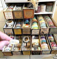 a drawer with many different types of washi tapes in it and someone holding a pen