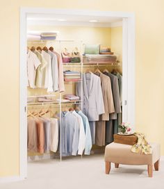 an open closet with clothes hanging on the wall and a footstool in front of it