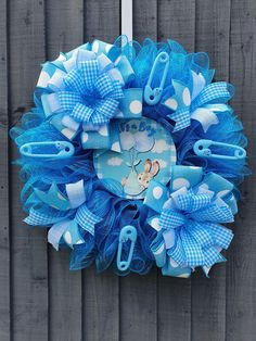 a blue and white wreath hanging on the side of a wooden fence with scissors attached to it