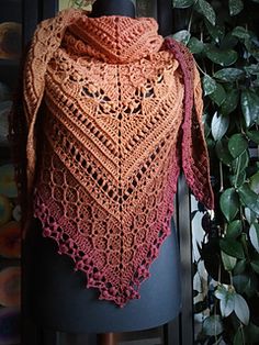 a crocheted shawl on a mannequin next to a potted plant