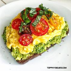 an omelet with tomatoes, avocado and other toppings on a white plate