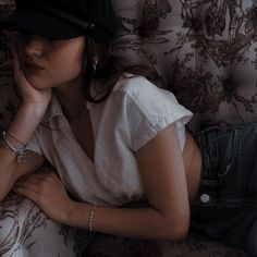 a woman laying on top of a couch wearing a hat