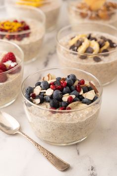 four bowls of oatmeal with fruit and nuts in them on a table