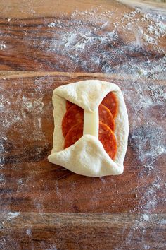 some kind of food that is sitting on a wooden table with flour all over it