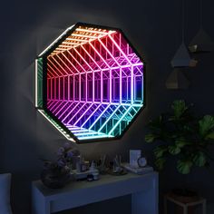 a colorful light up mirror on the wall next to a white table with a potted plant