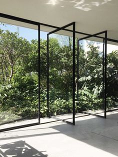 an empty room with glass walls and trees in the background