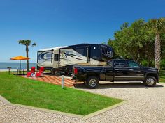 a black truck parked next to an rv on the side of a road near the ocean