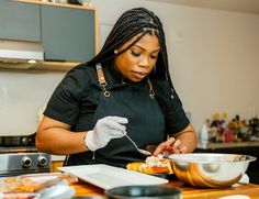 a woman in an apron and gloves is eating food from a bowl on the counter