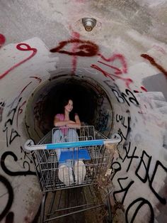 a woman sitting in a shopping cart with graffiti on it