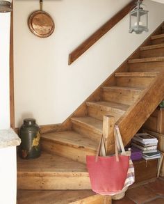 there is a red bag on the stairs in this house with wood floors and white walls