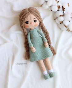 a knitted doll laying on top of a bed next to cotton