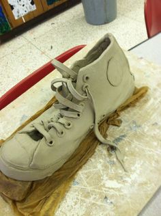 a pair of white shoes sitting on top of a piece of waxed paper next to a cup