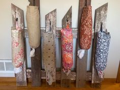 several different colored umbrellas hanging on wooden poles in a room with wood flooring