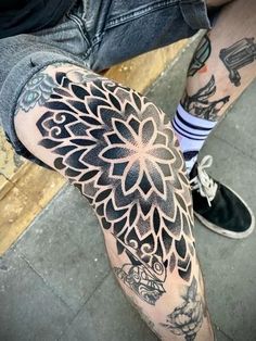 a man's leg with tattoos on it and an intricate flower design in the middle