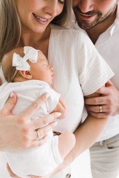 a man and woman holding a baby in their arms