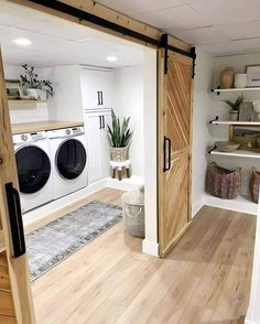 a washer and dryer in a room with wooden floors, white walls and open doors