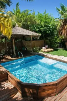 an outdoor swimming pool with wooden decking and palm trees in the backround