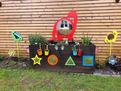 a wooden box with plants and pictures on it in front of a fenced area