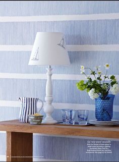 blue and white striped wallpaper in a dining room with vases, plates and cups on the table