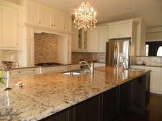 a large kitchen with marble counter tops and white cabinets, an island in the middle