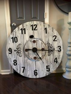 a white clock sitting on top of a hard wood floor next to a lamp and door