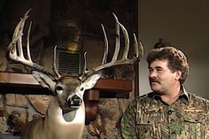 a man standing next to a deer with antlers on it's head