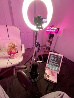 a pink room with a camera and laptop on the table next to a white chair