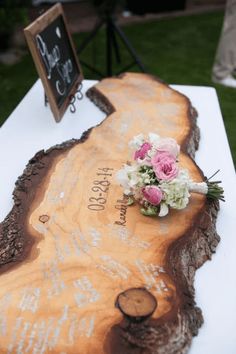 a wooden slab with flowers on it and a chalkboard sign