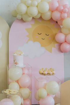 a table with balloons, cake and cupcakes on it in front of a pink backdrop