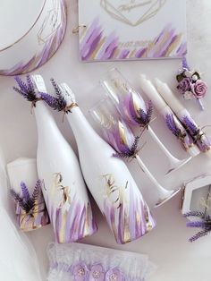 purple and gold wedding decorations with wine glasses, napkins, and candles on a white table