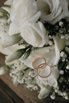 two wedding rings on top of white flowers