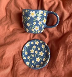 two cups and saucers sitting on top of a bed