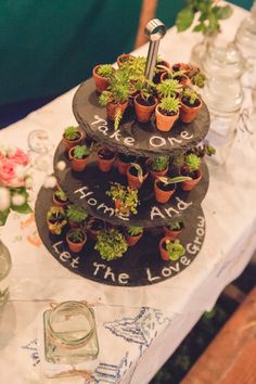 three tiered plant stand with potted plants on top and the words love are written on it