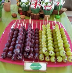 grapes and olives are on sticks in front of cupcakes