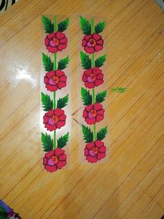 two stickers with flowers on them sitting on top of a wooden table next to a pair of scissors