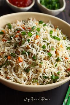 a bowl filled with rice, peas and carrots next to bowls of condiments