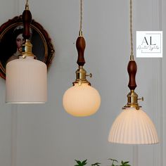 three lamps hanging from the ceiling in front of a mirror and vase with flowers on it