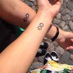 two people holding hands with tattoos on them