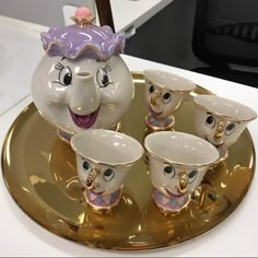 the tea set has five cups in it and is shaped like an elephant's head