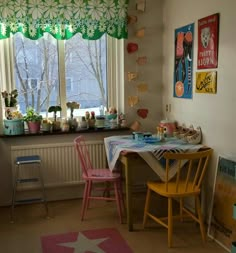 a table with two chairs next to a window in a room filled with posters and pictures