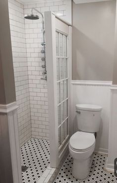 a white toilet sitting inside of a bathroom next to a walk in shower and tiled floor