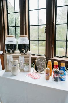 two wine glasses sitting on top of a white table next to bottles and saucers