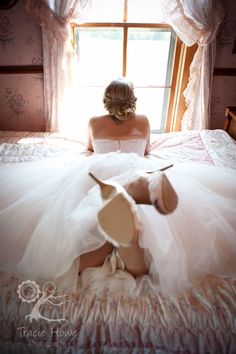 a woman sitting on top of a bed in a white dress and high heeled shoes