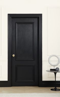 an empty room with a black door and side table on the floor next to it